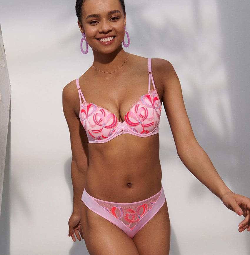 Woman smiling in front of white wall wearing the Marie Jo Vita Lingerie Set with matching Hoop Earrings